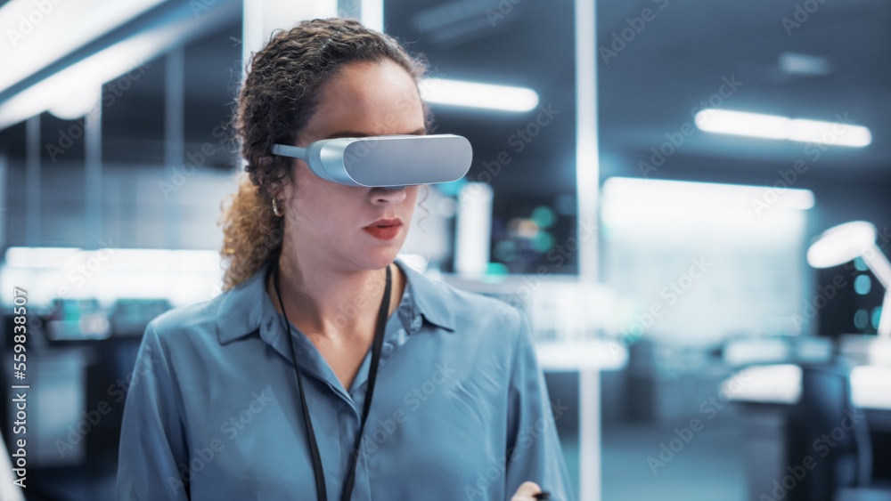 Portrait of a Female Engineer Using a Futuristic Virtual Reality Headset with Controllers to Operate