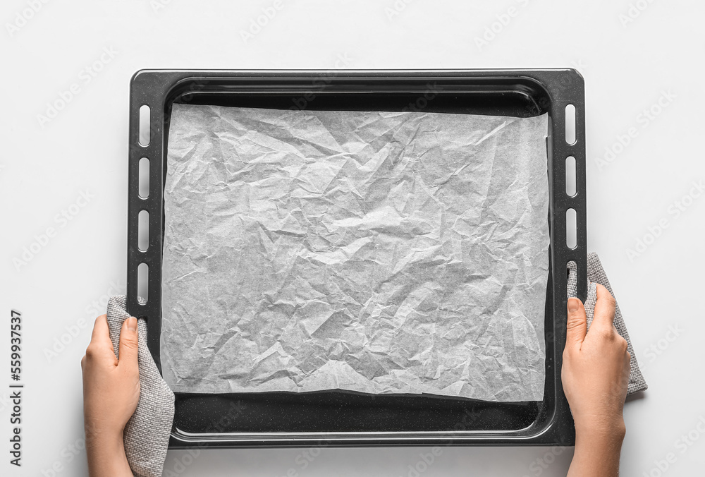 Woman with baking tray and paper on white background