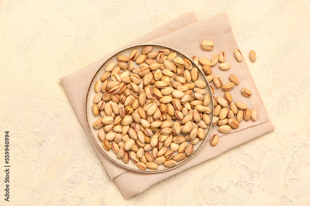 Napkin and board with tasty pistachio nuts on beige background