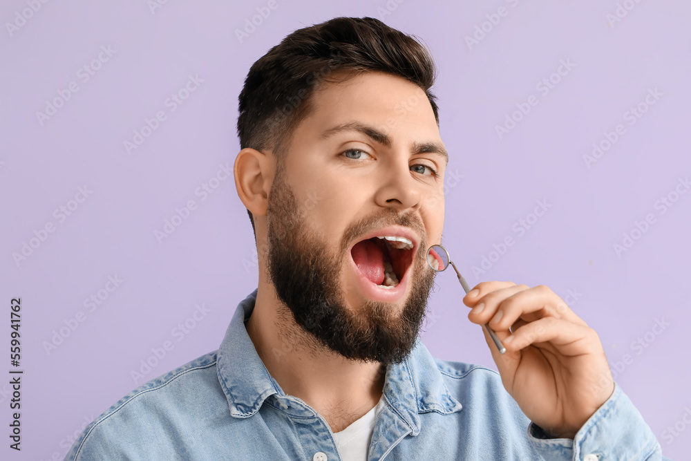 Young man with dental tool on violet background, closeup