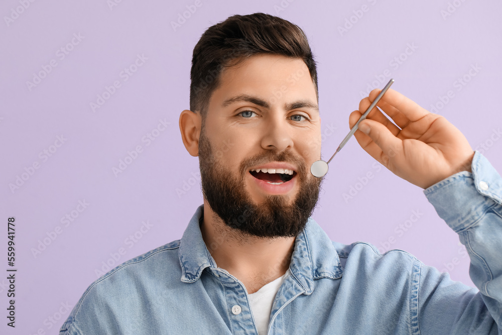 Young man with dental tool on violet background, closeup