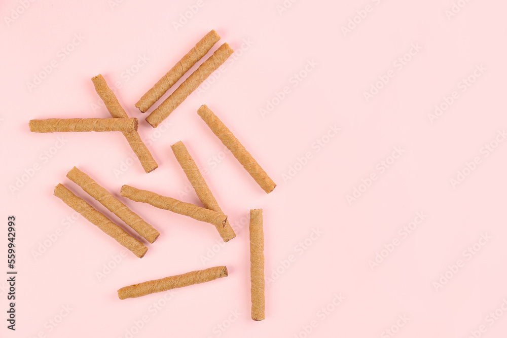 Tasty wafer rolls on pink background