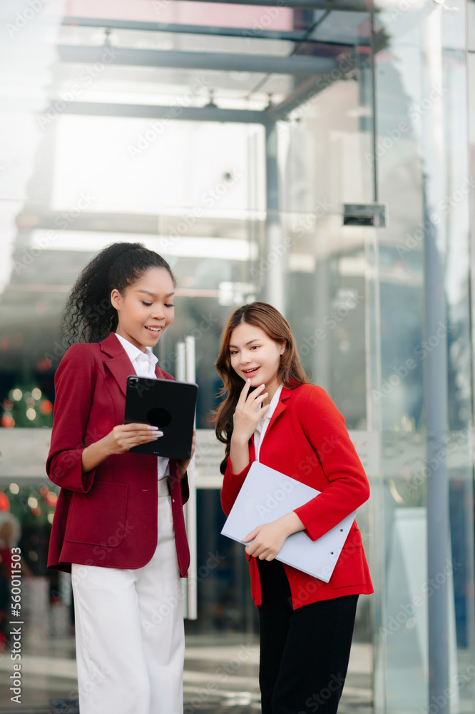 Businesswoman and woman going in city center in smart casual business style, talking, working togeth