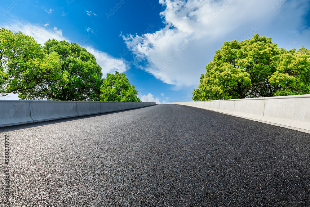 Asphalt road and green tree under the blue sky