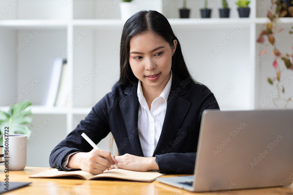 Businesswoman in office working with laptop and writing work schedule.