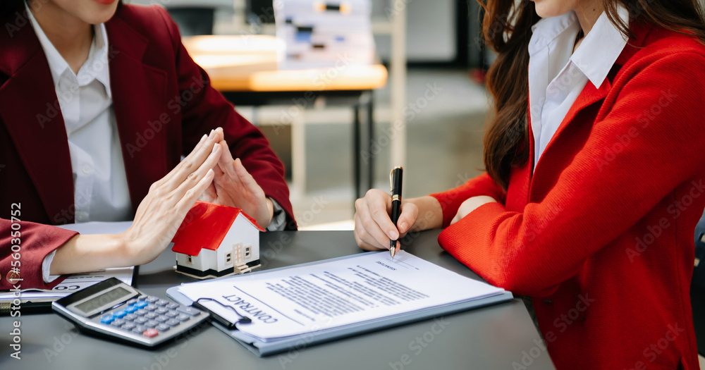 Female real estate agent is use hands to protect red roof for the concept of real estate investment 