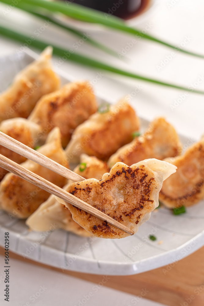 用酱油在白色桌子背景上的盘子里煎饺子饺子饺子。