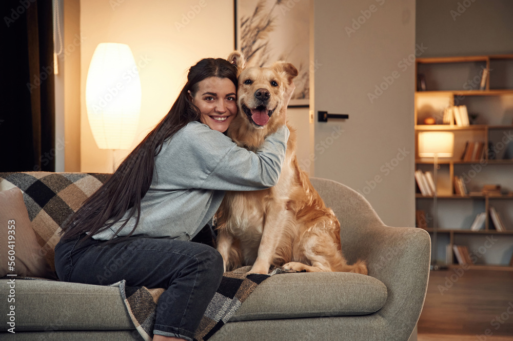 Playing and sitting on the sofa. Woman is with golden retriever dog at home