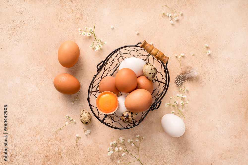 Eggs in metallic basket on beige background. Top view of raw brown eggs and white eggs with copy spa