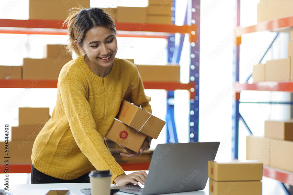 Woman who start up small business works in a warehouse. Startup entrepreneurs working with laptops c