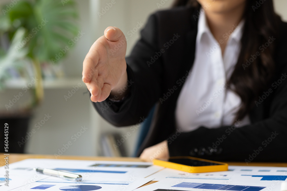 Portrait of charming Asian businesswoman in office looking smiling and shaking hands.