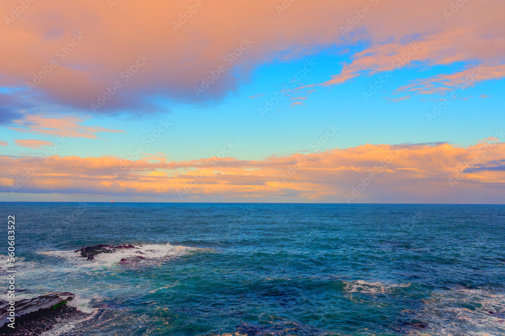 Rocky shore under blue sky and white clouds. White waves and moving white clouds Waimushan Seaside S