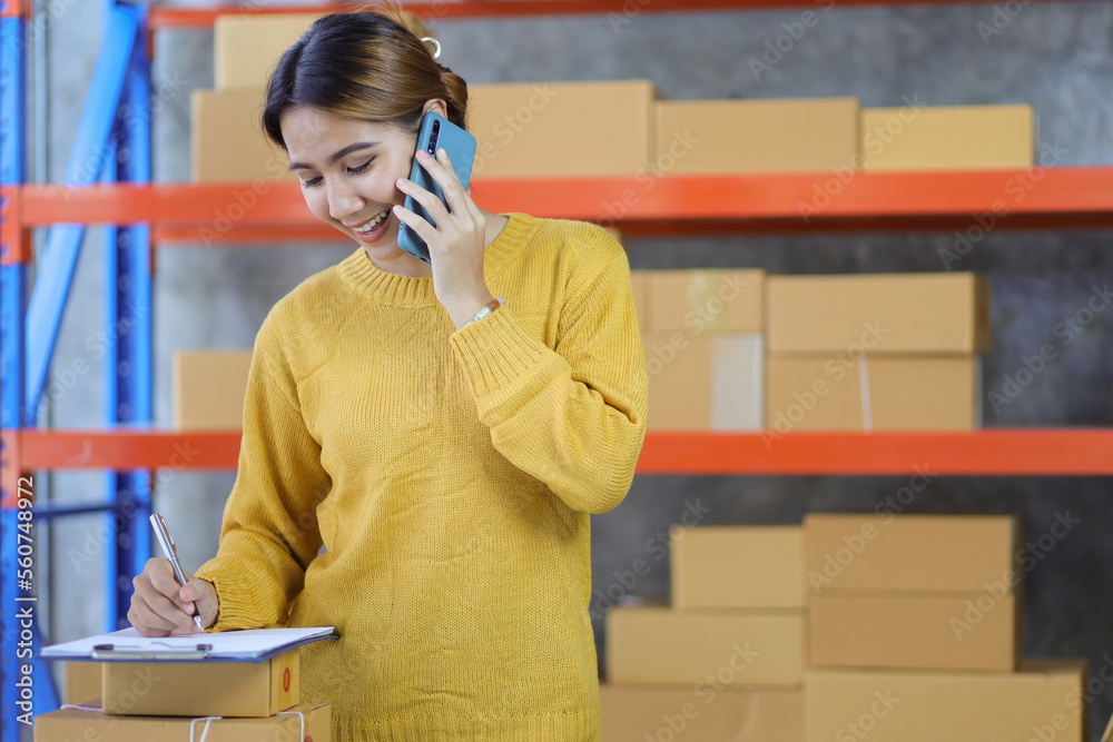 Woman who start up small business works in a warehouse. Start-up entrepreneur is writing a note on a