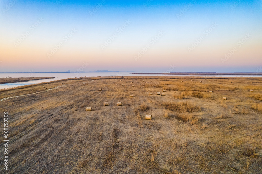 Aerial shot of the meadow and haystack after mowing by the lake in winter