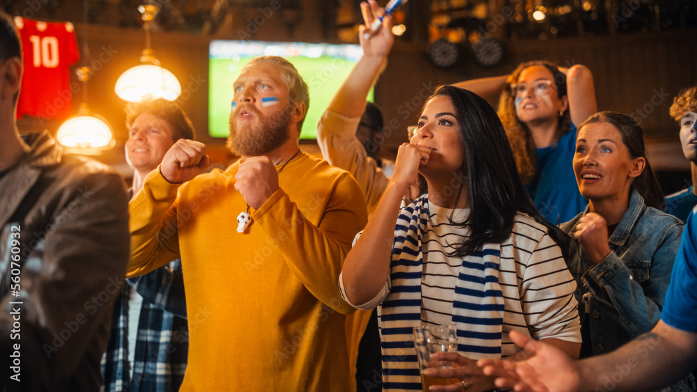 Group of Soccer Fans Watching a Live Football Match Broadcast in a Sports Pub on TV. People Cheering