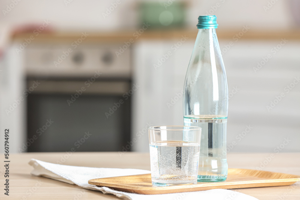 Board with bottle of water, glass and napkin on table in kitchen