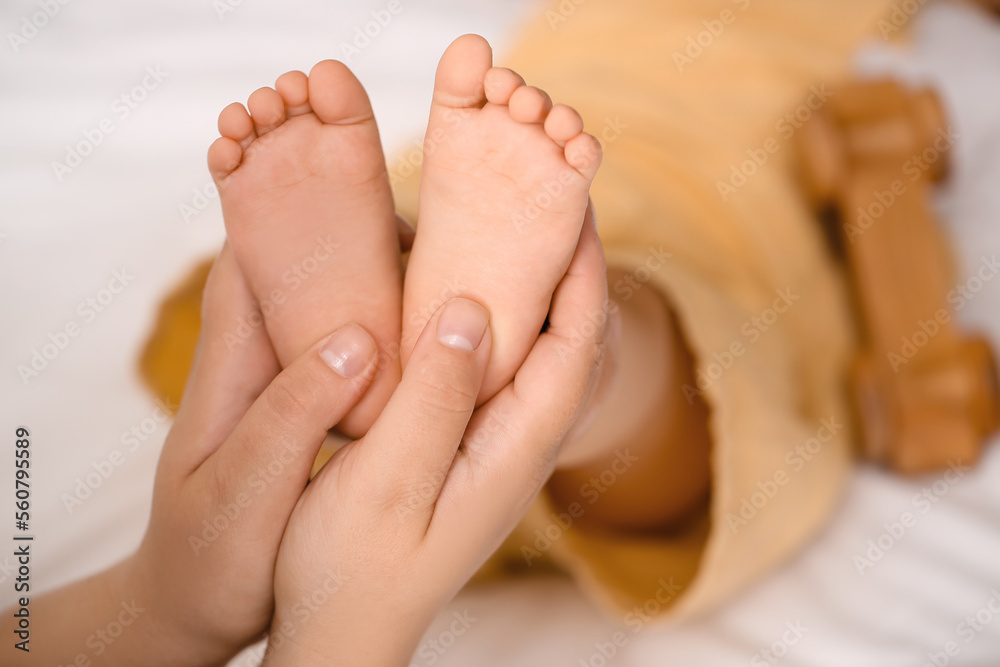 Mother massaging her babys feet in bedroom, closeup