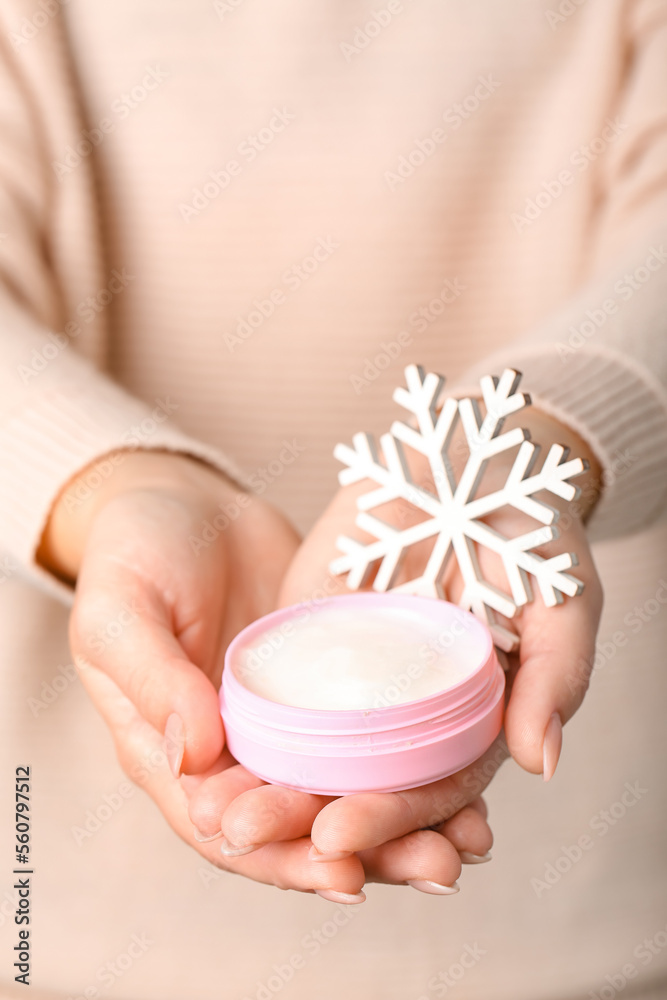 Woman holding jar of cream and decorative snowflake, closeup