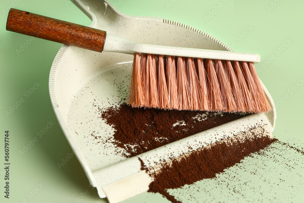 Dustpan with coffee and brush on green background, closeup