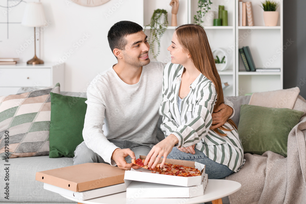 Happy young couple eating tasty pizza at home