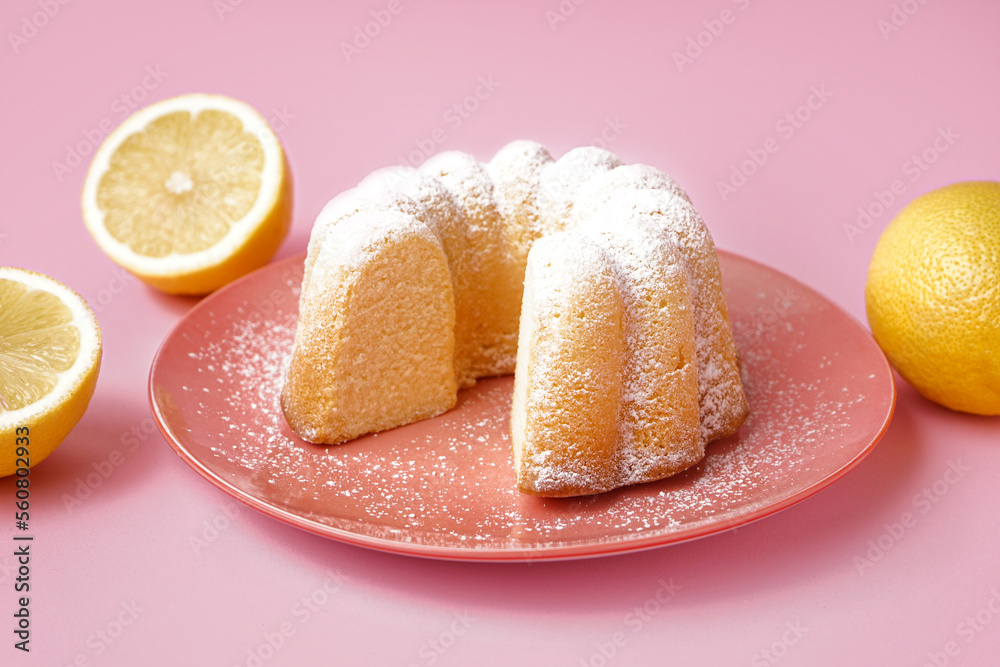 Plate with delicious cake and lemons on pink background