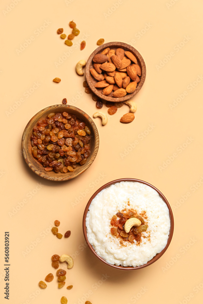 Bowl with delicious rice pudding, plates with raisins and almonds on beige background