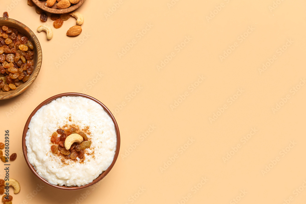 Bowl with delicious rice pudding, plates with raisins and almonds on beige background