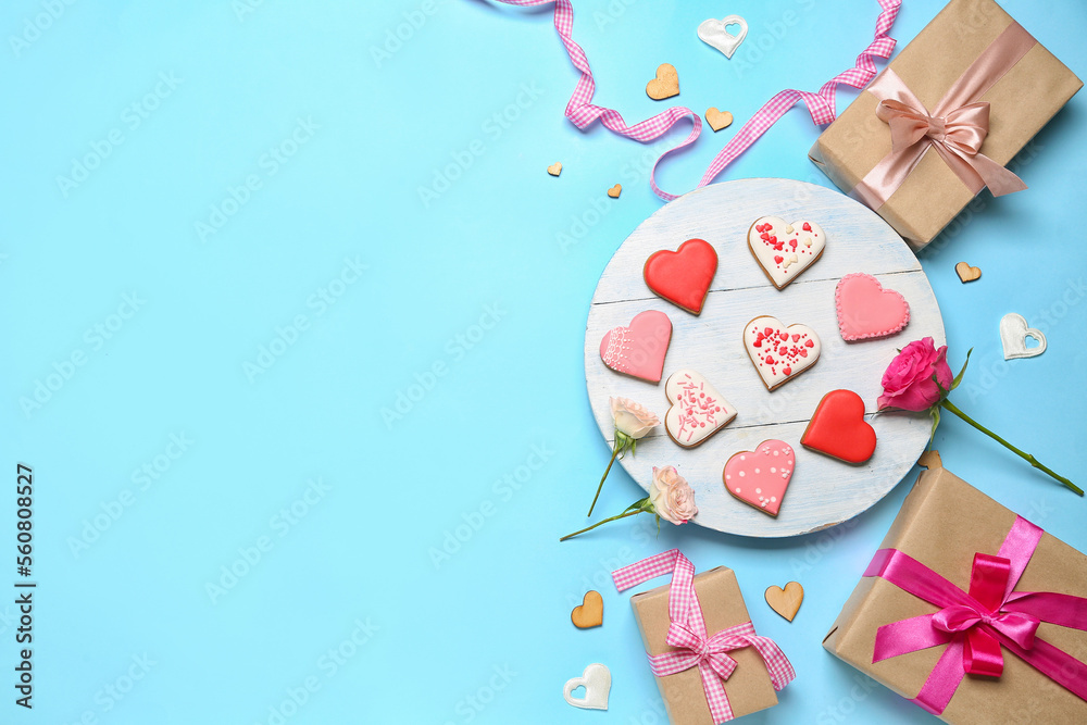 Composition with tasty heart shaped cookies, gift boxes and rose flowers on color background. Valent