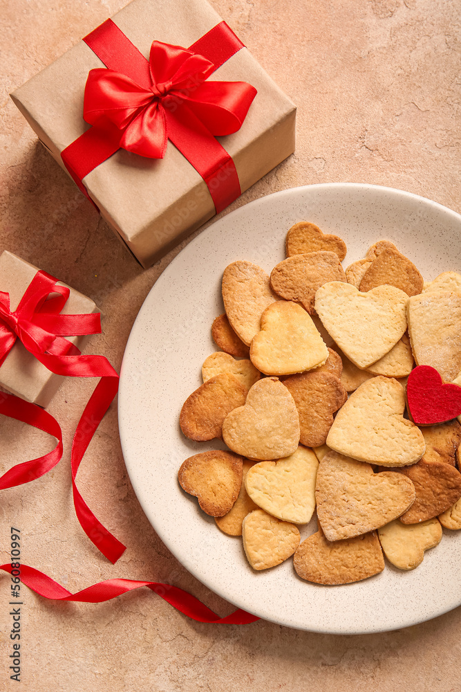 Plate with tasty heart shaped cookies and gifts on color background. Valentines Day celebration