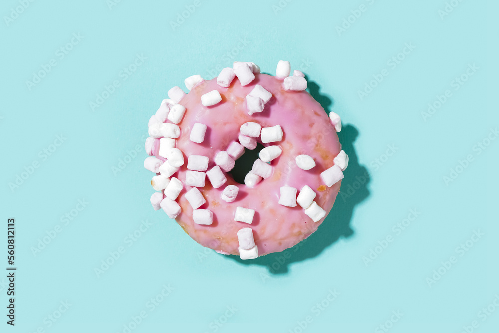 Delicious glazed donut with marshmallows on blue background