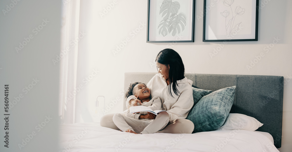 Story time, little girl laughing with her mom while reading a book