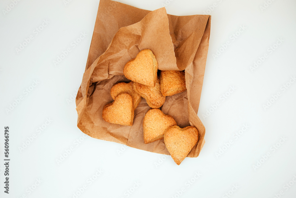 Shortbread cookies in the form of hearts in a brown paper bag on a white table. Top view