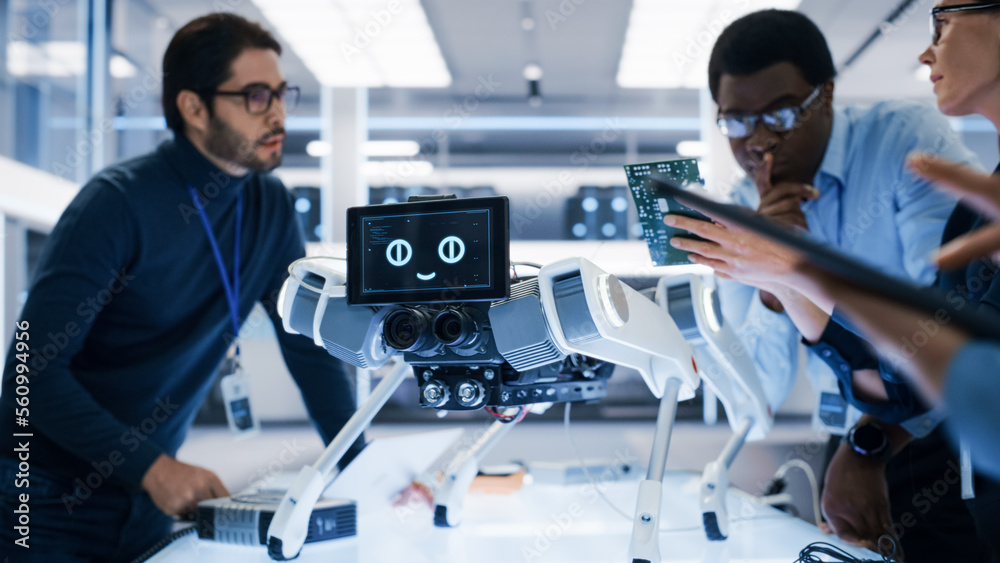 Portrait of Diverse International Team of Industrial Robotics Engineers Gathered Around a Table With