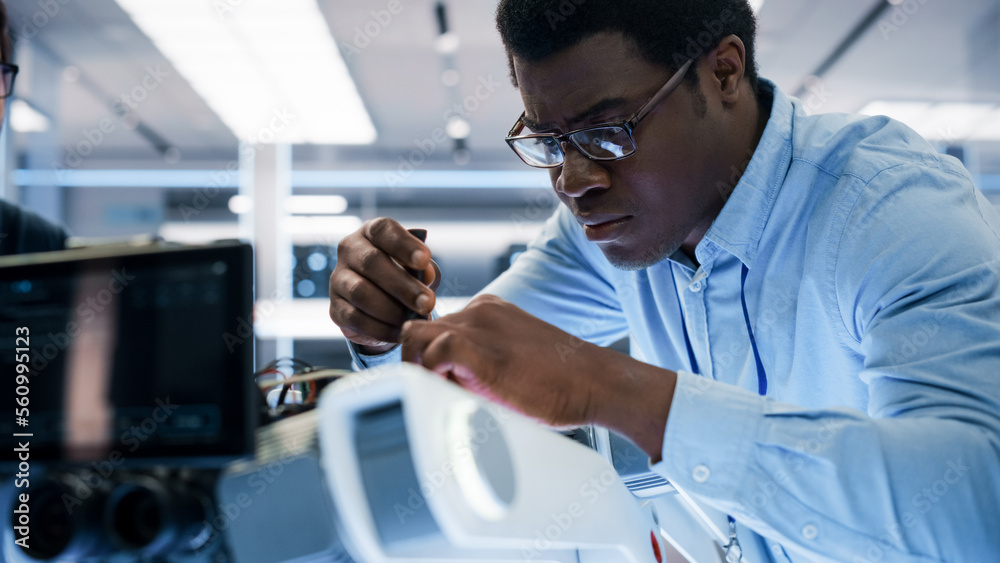 Close Up Portrait of an African American Robotics Engineer Setting Up a Robot Dog Prototype, Using a