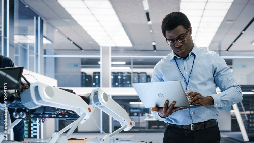 Smart Electronics Engineer Using Laptop Computer, Analyzing Robotic Machine Concept in a High Tech F