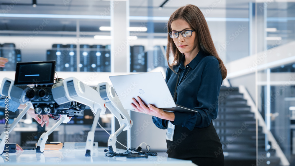 Portrait of a Young Robotics Engineer Using Laptop Computer, Analyzing Robotic Machine Concept in a 