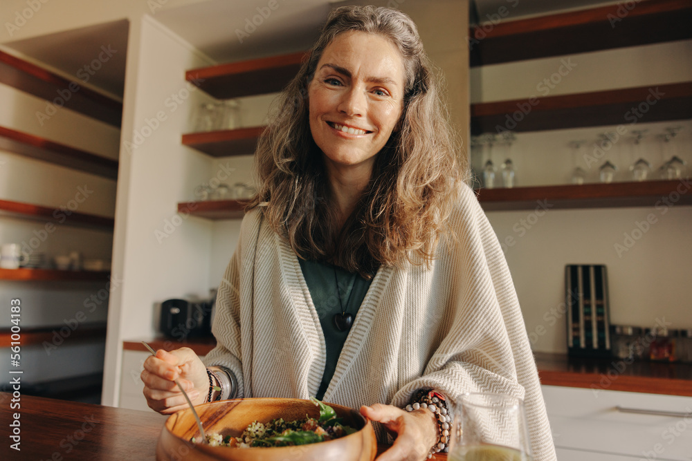 Mature woman smiling at the camera while having a buddha bowl