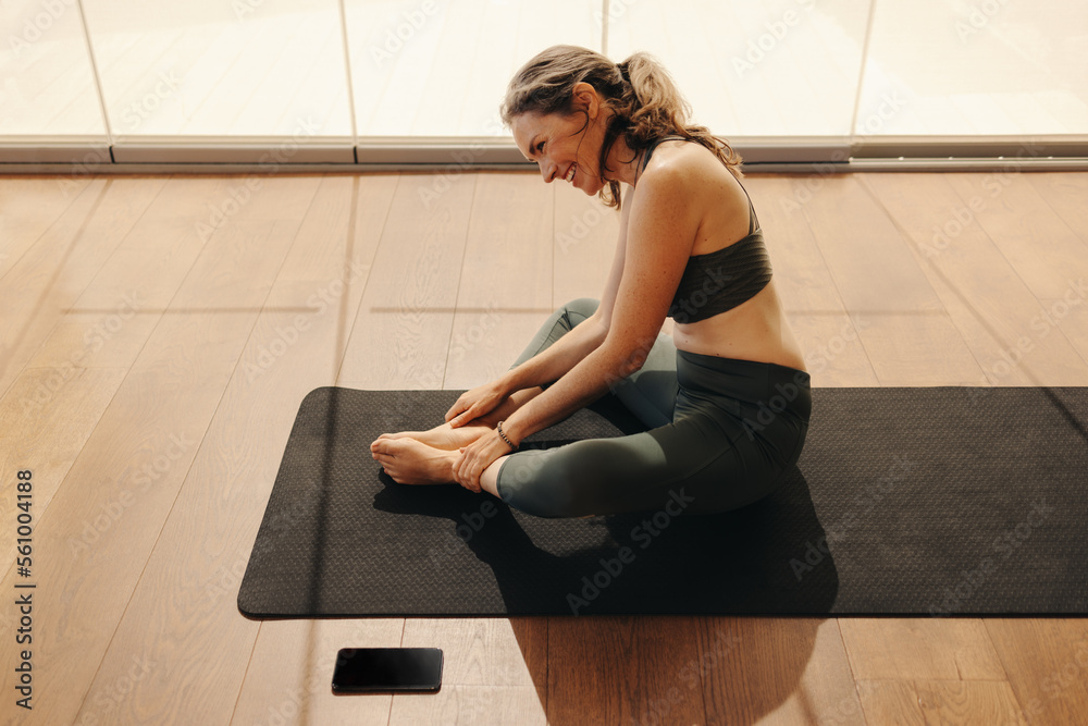 Happy senior woman doing a butterfly pose during yoga