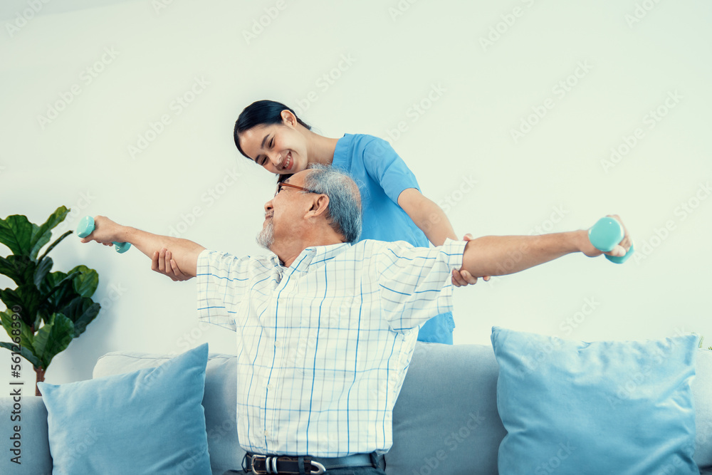 Contented senior patient doing physical therapy with the help of his caregiver. Senior physical ther