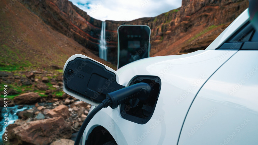 Electric car charging energy from charging station in the natural scenery, waterfall and stream back