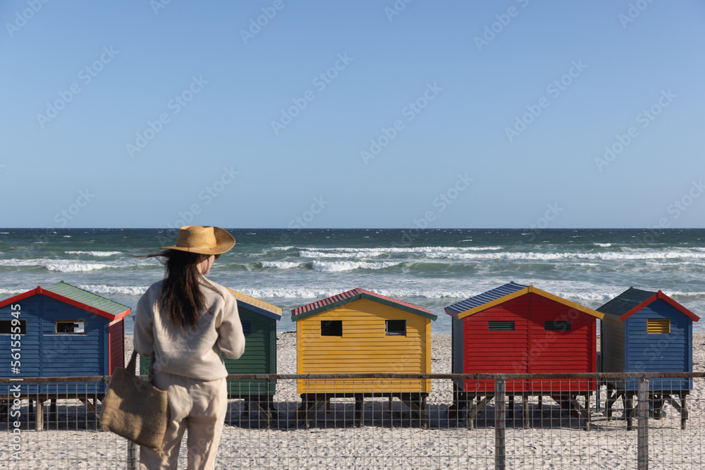 A woman looks out at the colorful beach huts of Muizenberg Beach