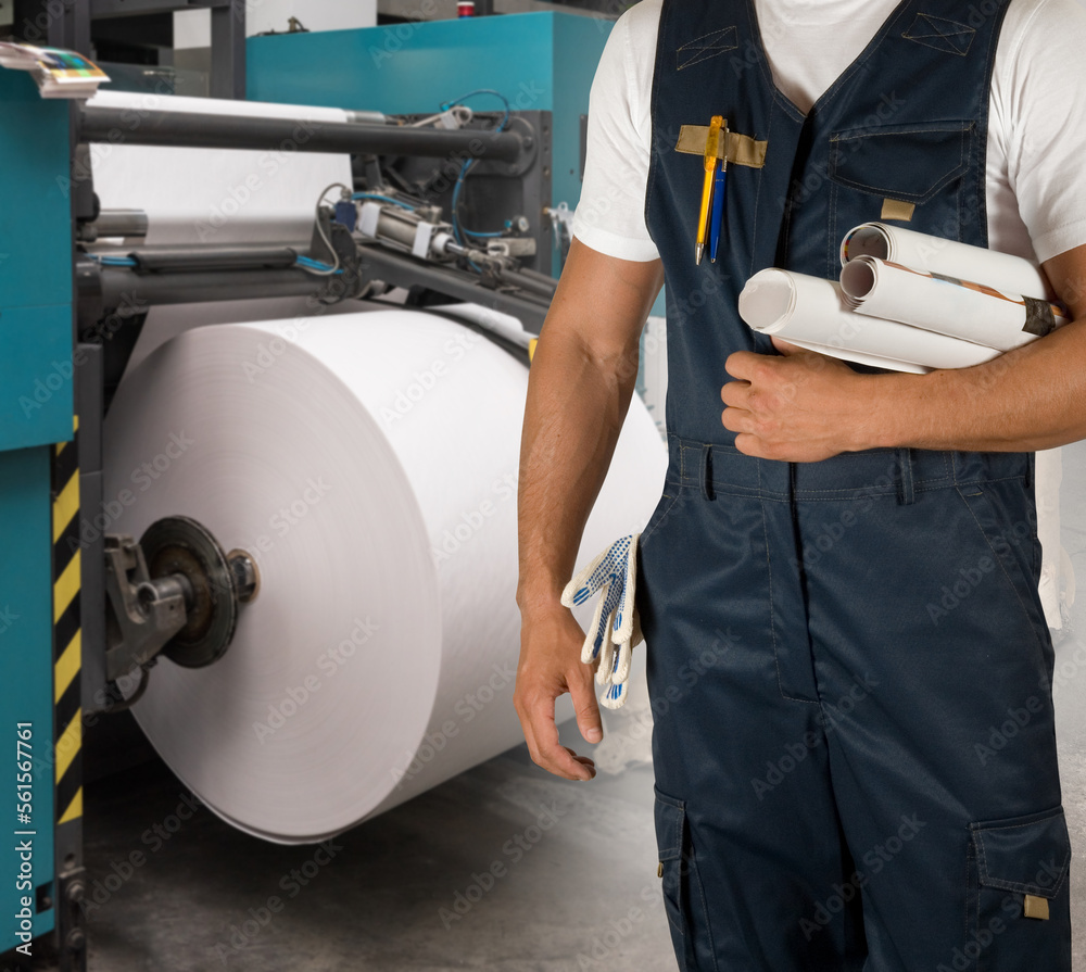 Man working in printing house with paper and printing machine