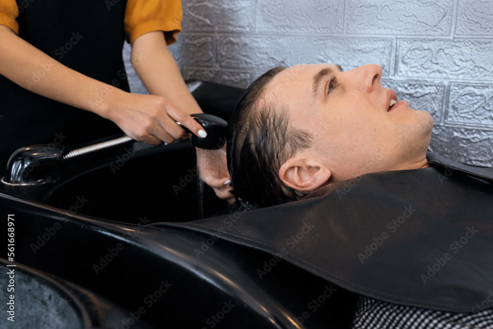 Closeup caucasian man getting hair wash by professional hairdresser with shampoo feels relax and com