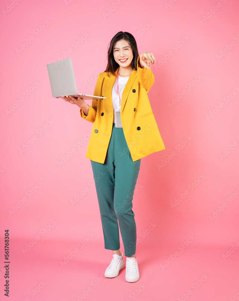 Full length image of young Asian bussinesswoman holding laptop on background