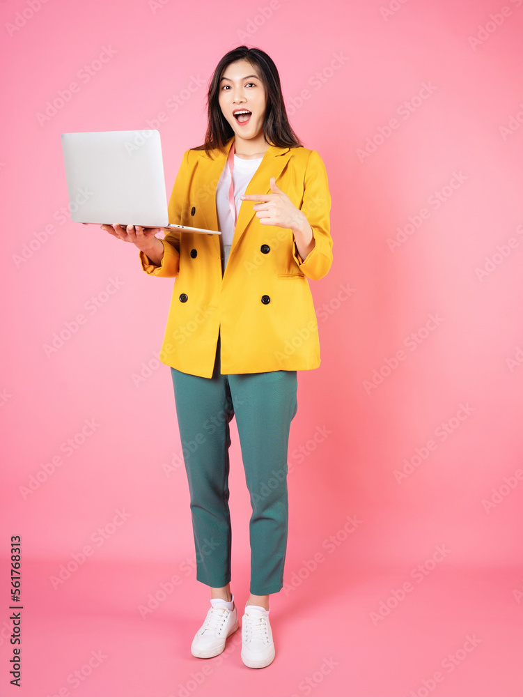 Full length image of young Asian bussinesswoman holding laptop on background