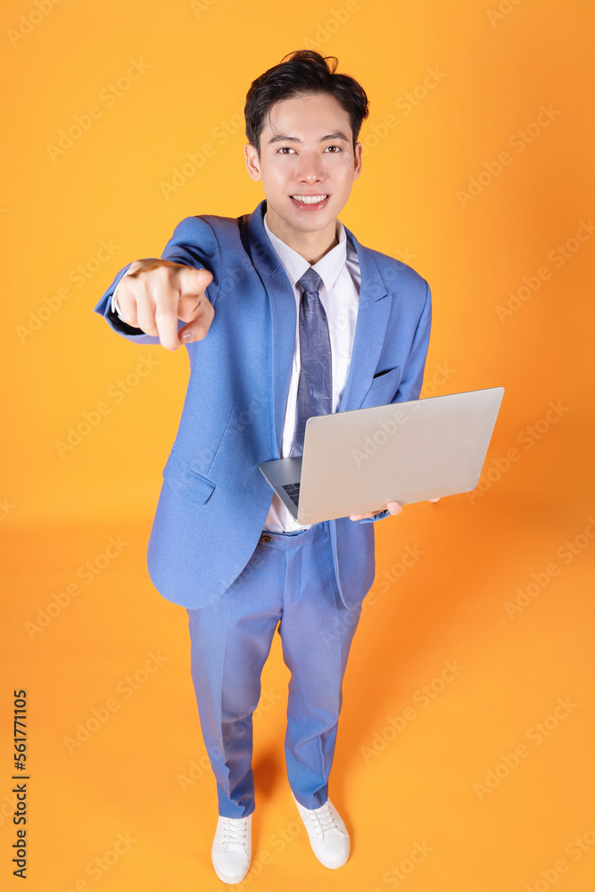 Image of young Asian businessman using laptop on background