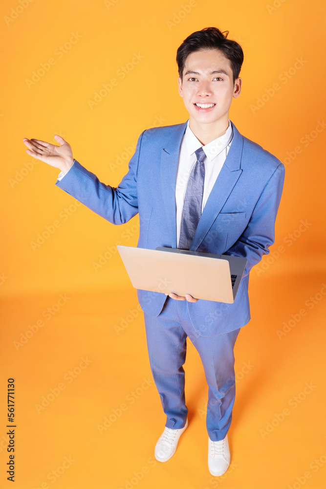 Image of young Asian businessman using laptop on background