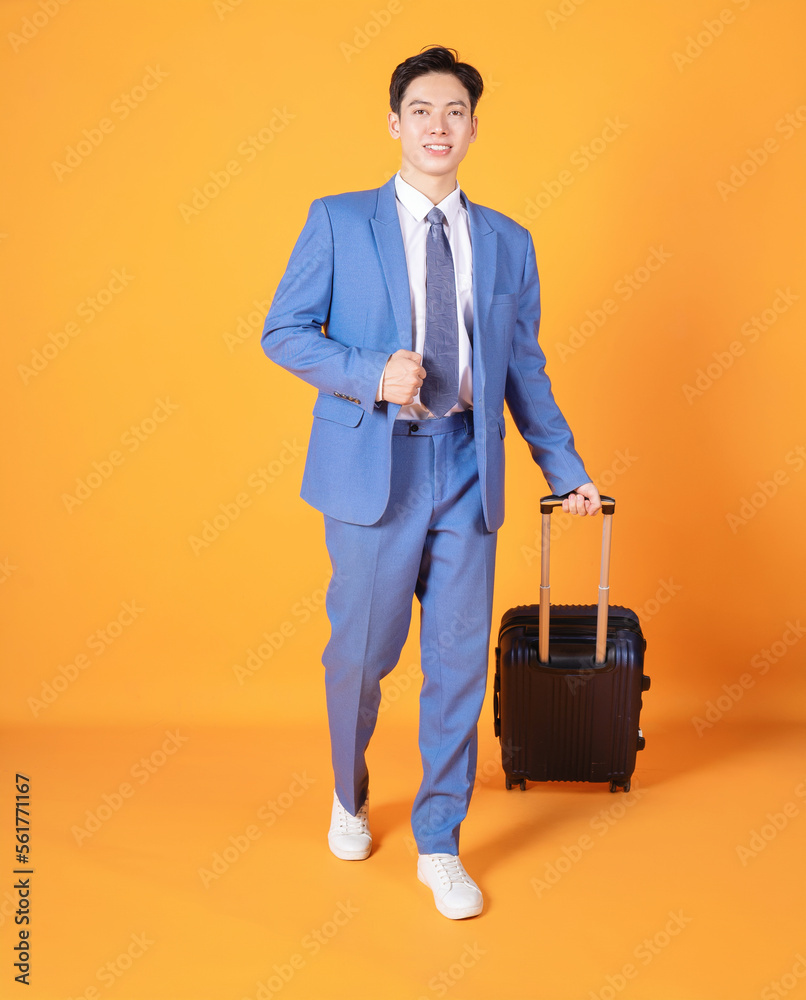 Image of young Asian business man holding suitcase on background