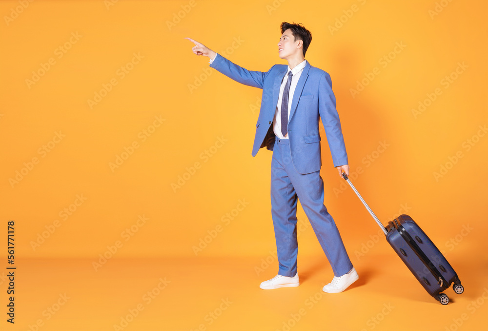 Image of young Asian business man holding suitcase on background