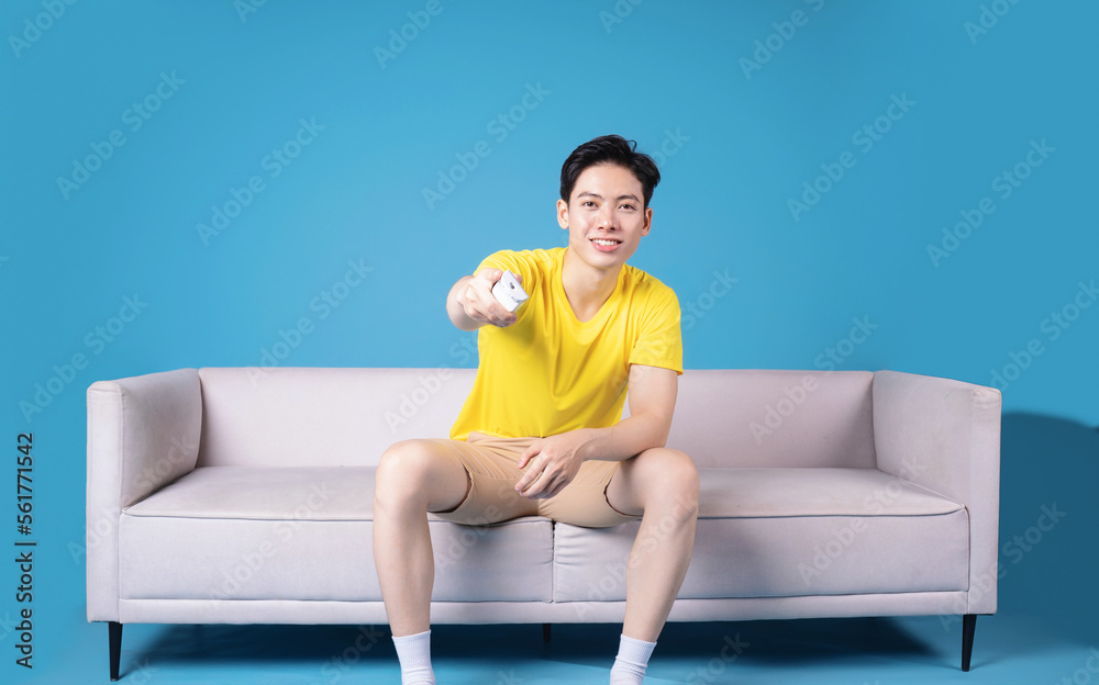 Image of young Asian man sitting on sofa